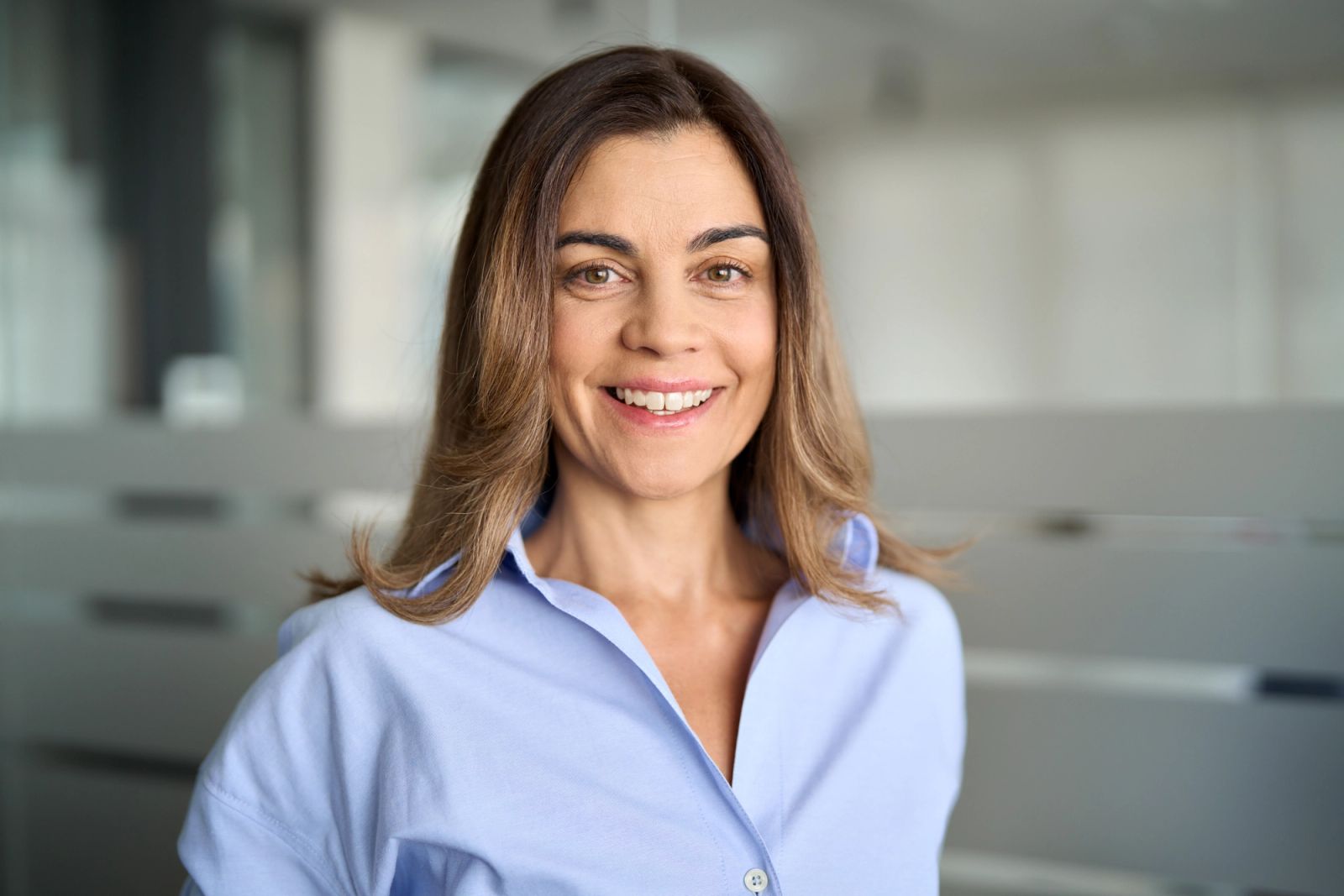 A smiling woman with brown hair in a light blue shirt.